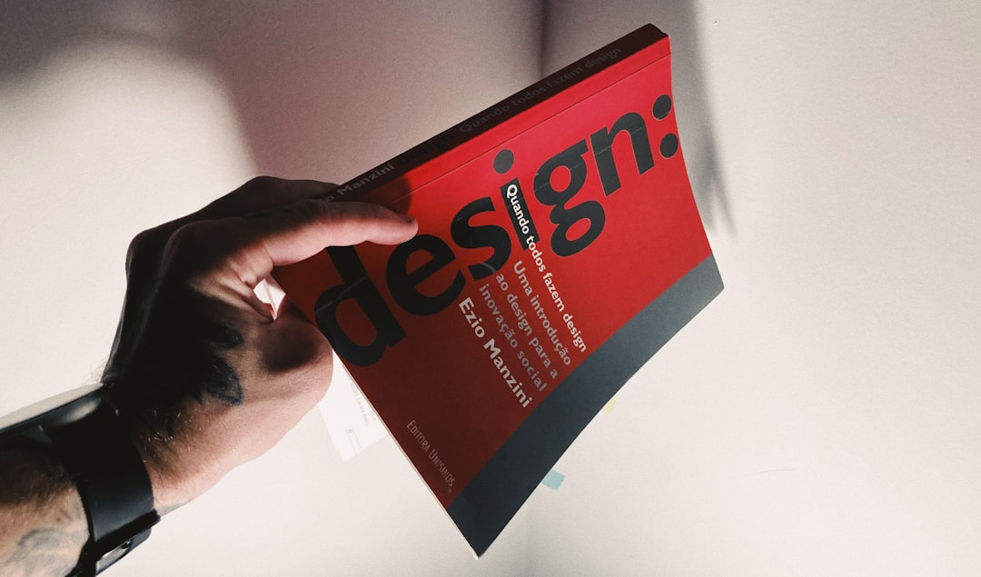 services-01 Tattooed hand holding a red book about design.